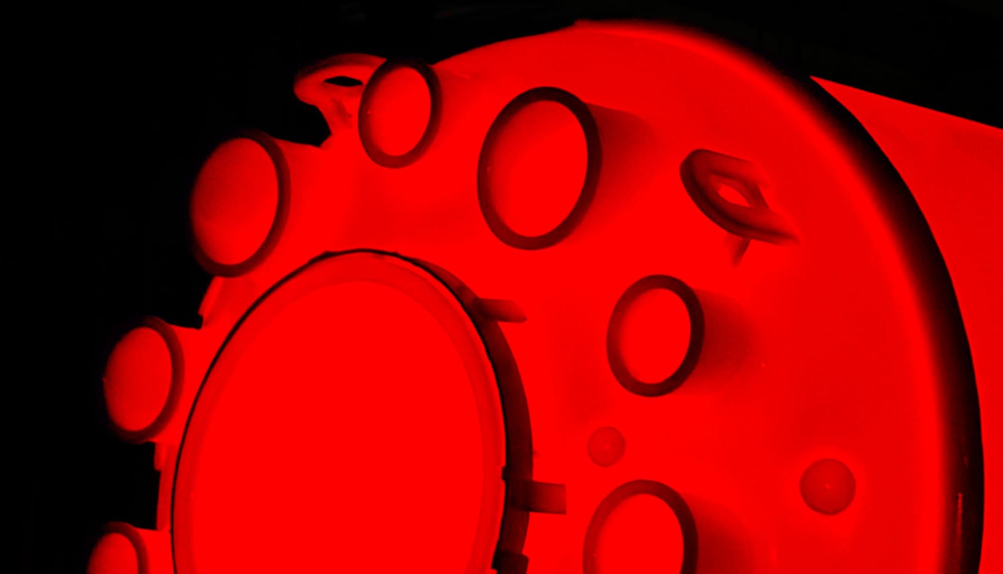 The top head of a glass lined reactor at firing temperature, its manway and nozzle openings glowing red in the furnace